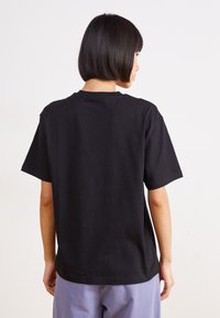 Camiseta de algodón negro con un corte relajado y mangas cortas. Diseñada con un escote redondo y una textura suave y sin adornos.