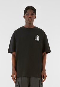 Sort kortærmet t-shirt lavet af bomuld, med et hvidt grafisk print på venstre bryst; afslappet pasform og glat tekstur.