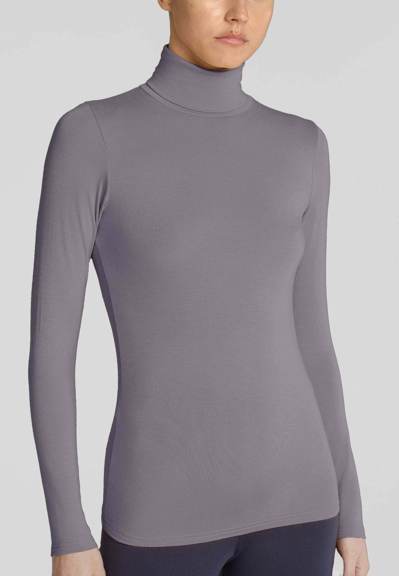 Maglione a maniche lunghe con colletto alto in un morbido e liscio tessuto grigio. Design aderente con colletto alto e polsini senza cuciture, caratterizzato da una silhouette pulita e minimalista.