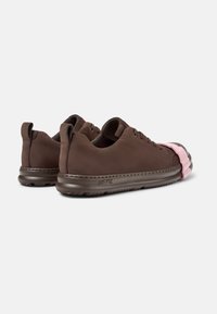Braune Wildledersneaker mit Gummisohle und pinkem Akzent an der Spitze. Das Design ist niedrig geschnitten, hat eine glatte Textur und minimale Nähte.