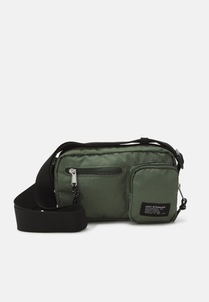 Sac bandoulière vert avec sangle noire réglable, deux compartiments zippés et une petite poche avant étiquetée "Levi Strauss."
