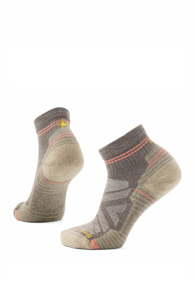 Par de calcetines deportivos de corte bajo en beige y gris con detalles en naranja, que cuentan con refuerzos en el talón y la punta.