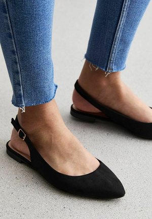 Black suede slingback flats with pointed toe design and a low heel. Features a minimalistic ankle strap with a gold-tone buckle.