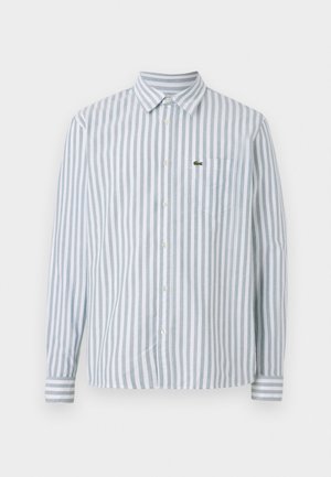 Striped long-sleeve shirt in light blue and white, featuring a button-up collar, front pocket, and a small logo detail on the chest.