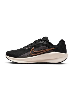 Zapatilla de running negra con una parte superior de malla transpirable, que presenta un diseño texturizado, el logo Nike en bronce y una entresuela acolchada en color crema.