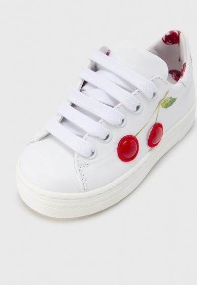 Baskets blanches avec de gros lacets blancs, broderie de cerise et appliqués brillants en forme de cerises rouges sur le côté, doublure intérieure florale visible.