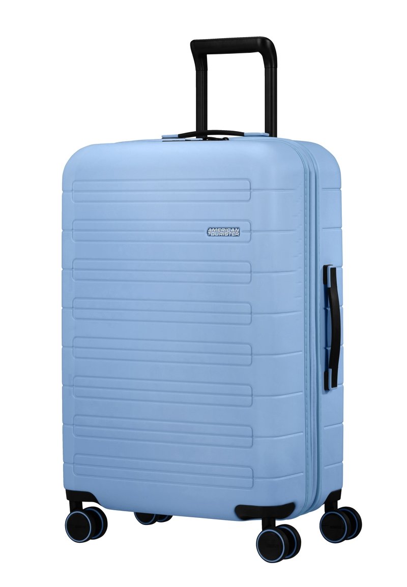Valigia rigida azzurro chiaro con quattro ruote girevoli doppie, maniglia telescopica nera e maniglia laterale per il trasporto.