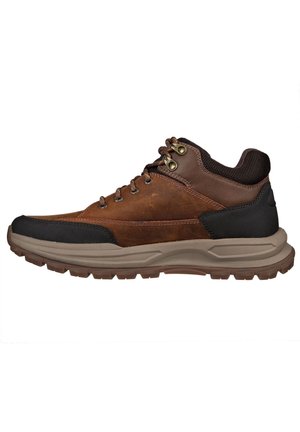 Scarpa da trekking in pelle marrone con accenti neri, punta arrotondata, occhielli metallici e parte superiore in tessuto testurizzato. Suola in gomma spessa e resistente per una buona aderenza.