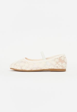 Ballerine transparente avec motif en dentelle florale, couleur beige, bout rond et une lanière fine autour de la cheville ; semelle en caoutchouc texturée.