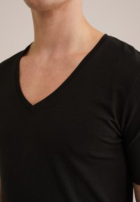 T-shirt nero a scollo a V realizzato in tessuto morbido e elasticizzato. Presenta un design aderente e maniche corte, evidenziando una texture liscia.