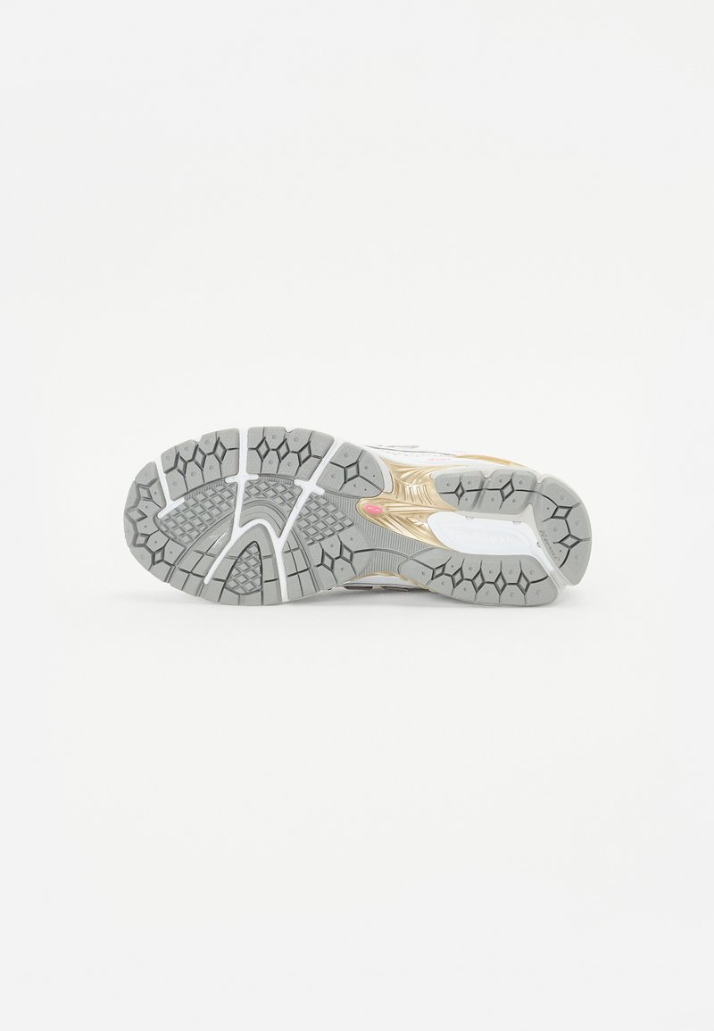 Suela de zapatilla de correr con un diseño de goma gris que presenta patrones texturizados y una forma aerodinámica, acentuada con elementos dorados y blancos.
