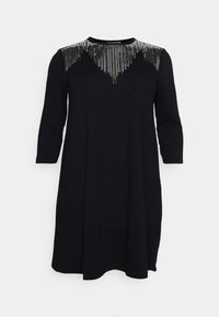 Svart klänning med trekvartsärmar, prydd med ett silverfärgat paljettmönster över bröstet. Mjuk tyg, A-linjeform, knälång.