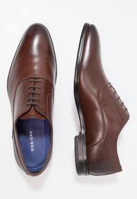 Chaussures habillées en cuir marron avec une finition lisse, un design à lacets et des semelles intérieures bleu contrasté. Présente un détail subtil texturé au niveau du talon.