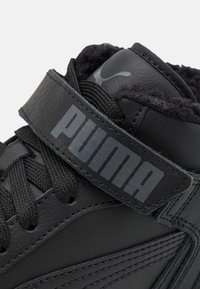 Černé vysoké tenisky s koženým svrškem, texturovanými tkaničkami a suchým zipem se znakem "PUMA" v kontrastní šedé barvě.