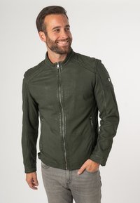 Groene leren jas met een staande kraag, ritssluiting aan de voorkant, zijzakken en gestikte details op de schouders en mouwen.