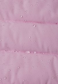 Różowy, wodoodporny materiał z wypukłymi częściami i widocznymi kroplami wody na powierzchni, prezentujący gładką teksturę i równomierne przeszycia.