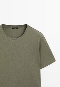 T-shirt kaki à manches courtes et col rond avec une étiquette noire "Massimo Dutti" à l'intérieur du col.