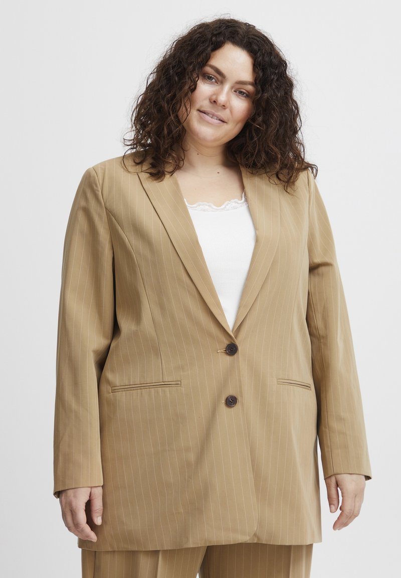 Barna csíkozott blézer, két elülső zsebbel és két gombbal, kivágott hajtókával és enyhén laza szabással. Az anyaga sima.