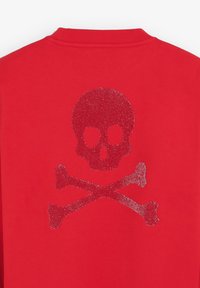 Tissu rouge avec un motif de tête de mort et de tibias scintillante en rouge foncé, centré sous un col à côtes sur un vêtement.