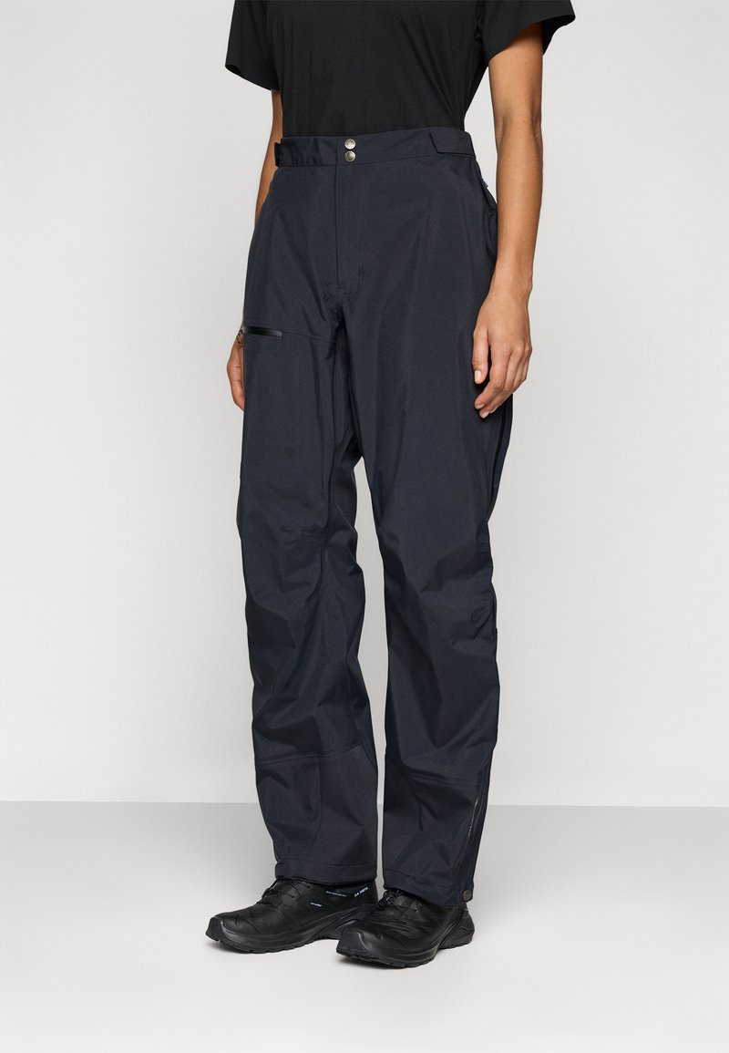 Zwarte waterdichte broek, losse pasvorm met een soepele textuur. Bevat een ritszak op de dij en twee metalen knopen in de taille.