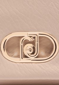 Borsa in pelle beige con chiusura ovale in metallo dorato dal design intrecciato e logo in rilievo. Texture liscia con dettaglio di grana sottile.