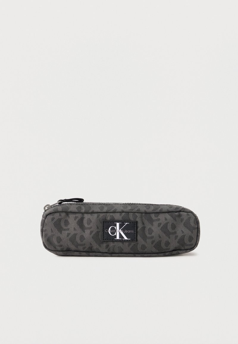 Σκούρο γκρι τσαντάκι Calvin Klein Jeans με φερμουάρ, επαναλαμβανόμενο μοτίβο «CK» και κεντρικό λογότυπο σε απλό φόντο.