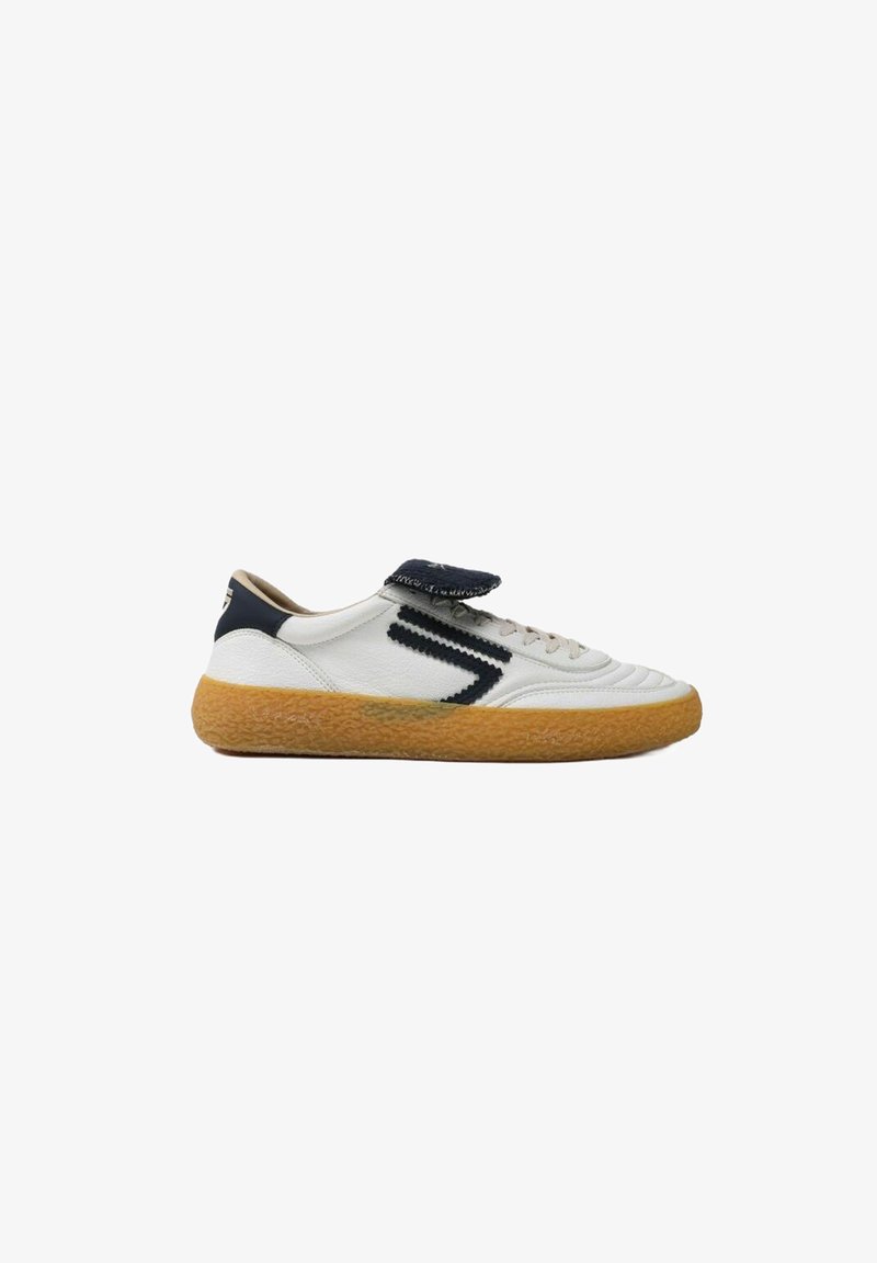 Hvide lædersneakers med marineblå accenter, en struktureret tan gummisål og en velcro-rem på toppen. Har syninger som detalje.