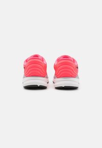 Chaussures avec une tige lisse et vibrante de couleur rose, dotées de détails texturés, d'une semelle intermédiaire grise contrastante et d'une semelle extérieure en caoutchouc noire.