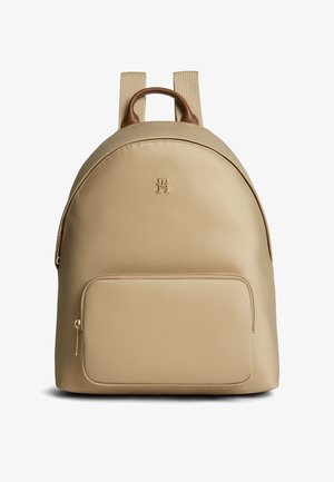Beige læder rygsæk med front lynlåslomme, beige stof skulderstropper og brun læder top-håndtag, med et lille præget logo.
