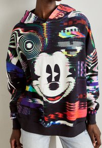 Sudadera negra con capucha que presenta un gran gráfico estilizado de Mickey Mouse, con patrones digitales coloridos y un diseño de tela texturizada.