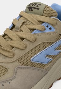 Μπεζ αθλητικό παπούτσι με υλικά από δίχτυ και σουέντ, με μπλε λεπτομέρειες, στρογγυλά κορδόνια, λογότυπο στη γλώσσα και υφή στην σόλα.