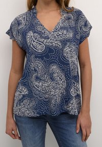 Námořnická modrá blůza s výstřihem do V, krátkými rukávy a bílými paisley vzory. Vyrobena z lehkého materiálu s volným střihem.