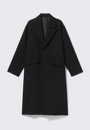 Zwarte lange wollen jas met ingesneden revers, drie knopen aan de voorkant en twee klepzakken, plat uitgestald op een lichte achtergrond.