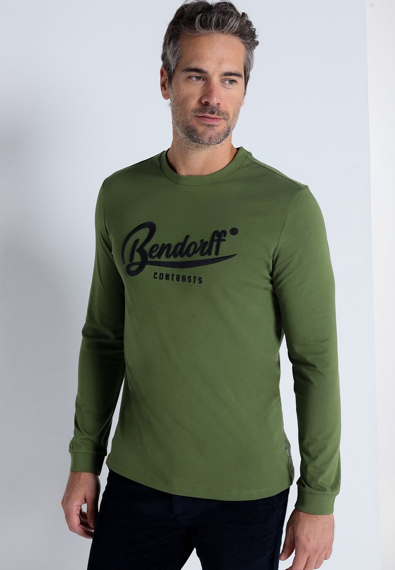 Long-sleeve olive green shirt with a round neckline. Features a black printed logo saying "Bendorff" across the chest in a cursive font.
