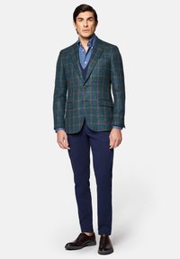 Marynarka w kratę w odcieniach zieleni i niebieskiego, zestawiona z niebieską koszulą i granatowymi spodniami. Brązowe buty dopełniają stylizację. Dopasowany krój i wyrazisty design.