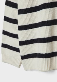 Tissu tricoté de couleur crème avec de larges rayures horizontales noires et ourlet côtelé ainsi que poignets sur une manche de pull.