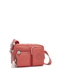 Coral nylon crossbody bag with multiple zippered pockets, contrasting cream trim, adjustable strap, and a decorative monkey charm.
