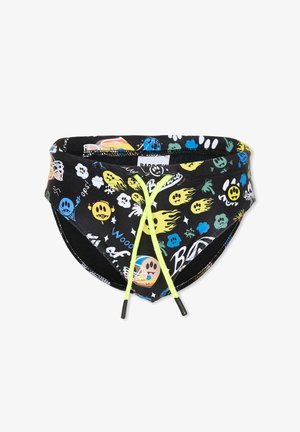 Bañador tipo slip negro con estampados coloridos de caras sonrientes estilo dibujos animados, llamas y textos, con cordones delanteros de color amarillo brillante.