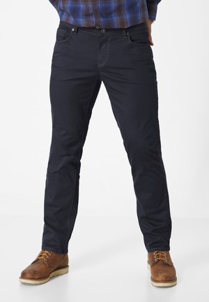 Dark blue pants made of cotton blend, featuring straight legs, contrasting stitching, and front pockets, worn with brown lace-up boots.