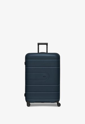 Maleta rígida de color azul oscuro con una superficie texturizada, ranuras horizontales, un mango telescópico y cuatro ruedas giratorias negras.