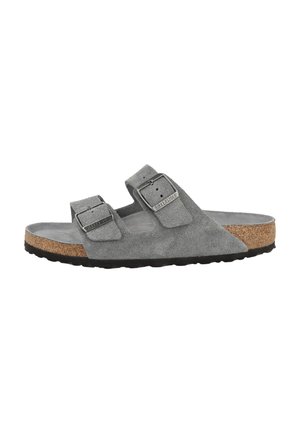 Grijze suède Birkenstock sandaal met twee verstelbare banden, kurken voetbed en zwarte rubberen zool, gezien vanaf de zijkant.