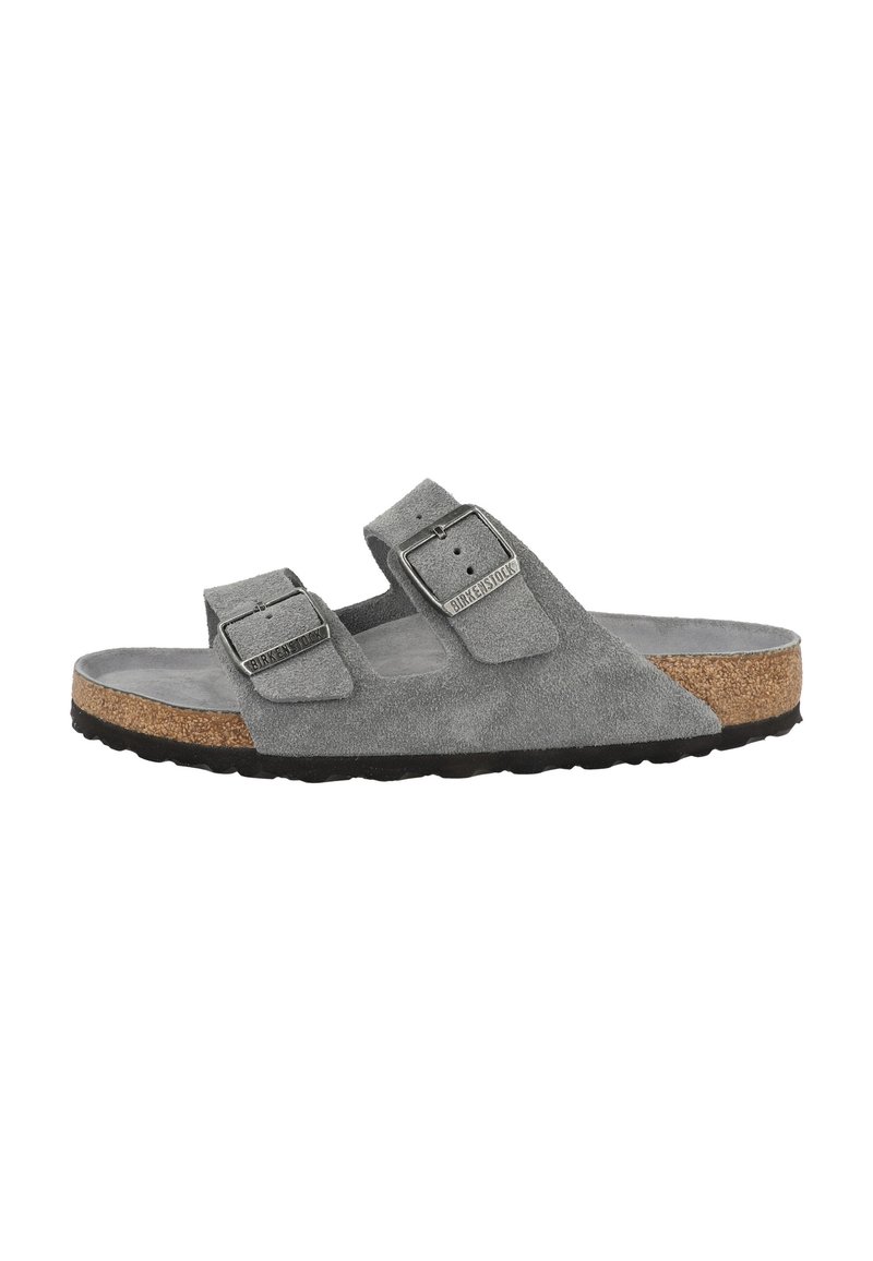 Grijze suède Birkenstock sandaal met twee verstelbare banden, kurken voetbed en zwarte rubberen zool, gezien vanaf de zijkant.
