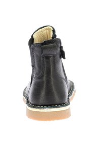 Stivaletto in pelle nera con punta arrotondata, zip posteriore e suola in gomma marrone chiaro con dettagli di cucitura leggeri.