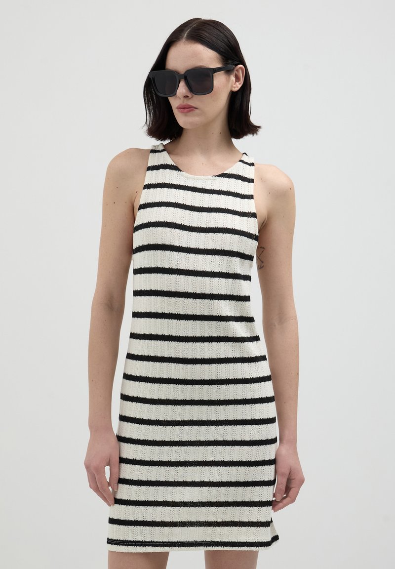 Abito senza maniche a righe in un tessuto a maglia, con strisce nere su uno sfondo bianco, caratterizzato da una silhouette aderente e scollatura rotonda.