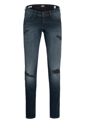 Jeans ajustados de color azul oscuro con parches desgastados en los muslos y las rodillas, cierre frontal con botón y cremallera, estilo de cinco bolsillos.