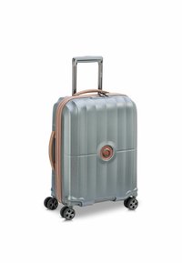 Valigia rigida con spinner di colore azzurro chiaro, superficie testurizzata, zip e maniglia bicolore, quattro ruote, serratura integrata con dettagli del logo.