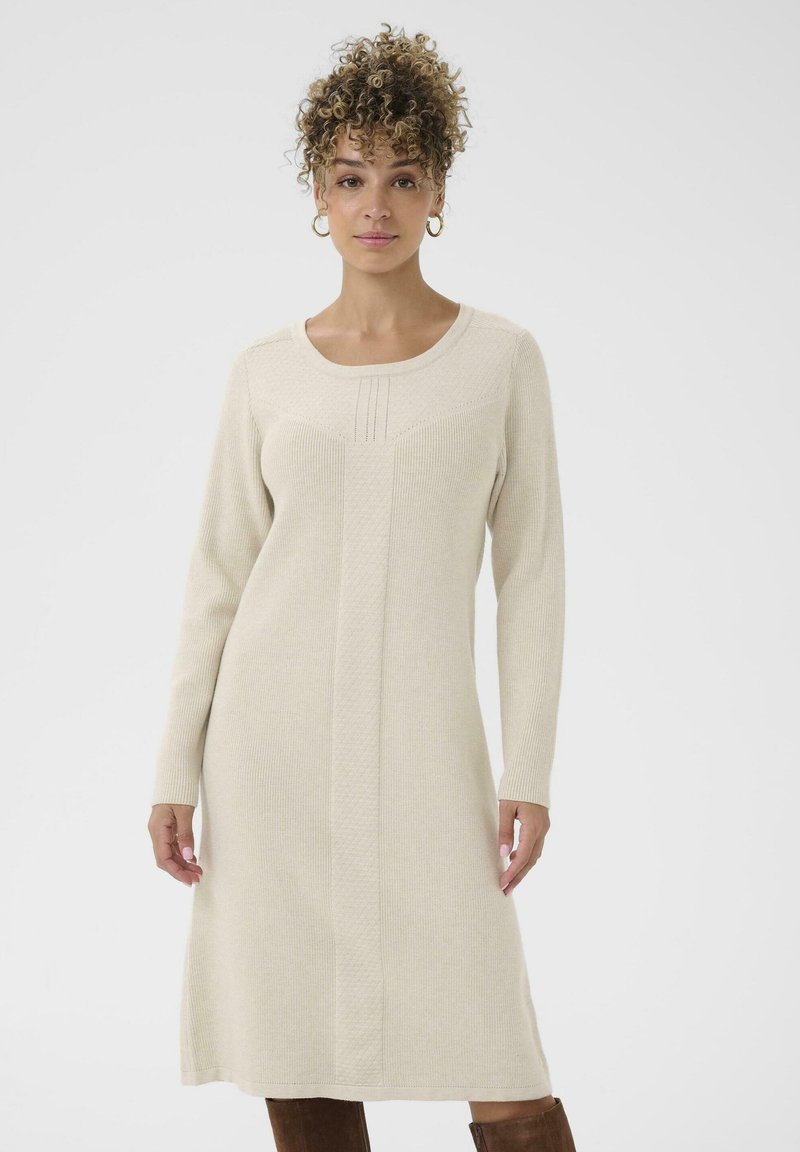 Hosszú ujjú kötött ruha krémszínben, kerek nyakkivágással, texturált mintázattal és enyhén bővülő szegéllyel. Simaságát a bordás anyag adja.