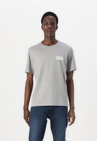 Graues Baumwoll-T-Shirt mit Rundhalsausschnitt und kurzen Ärmeln, mit einem weißen "JACK & JONES"-Logo auf der linken Brustseite.