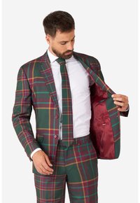 Zelený kostým s kostkovaným vzorem a burgundskými a zlatými akcenty, vybavený sako na dva knoflíky a odpovídající kravatou. Podšívka v burgundské barvě.