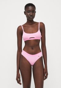 Roze bikini set met een cropped top met een uitsnijding aan de voorkant en bijpassende lage onderbroekjes. Gemaakt van textuurstof met subtiele branding.